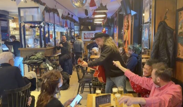Koopzondag Leuven Johnny Trash met rode guitaar in cafe